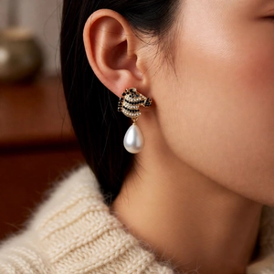 Macro view of vintage zebra-shaped earring with crystals and teardrop pearl on a model