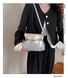 Close-up of metallic silver crossbody bag featuring a round golden push-lock closure