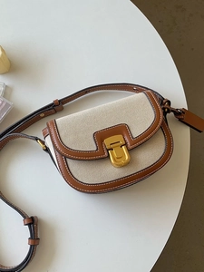 Borsa a sella retrò in pelle marrone e tela beige su superficie bianca