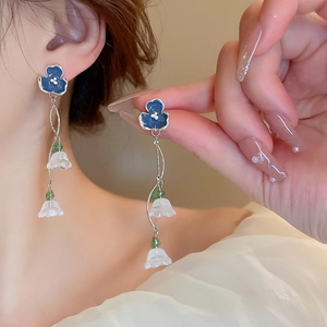 Detail of blue and white lily of the valley earrings with silver chain on model
