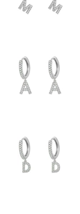 Macro view of silver alphabet hoop earrings with micro-pave M, A, and D letter charms