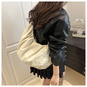 Detailed view of cream-white oversized pleated hobo bag worn with a stylish outfit
