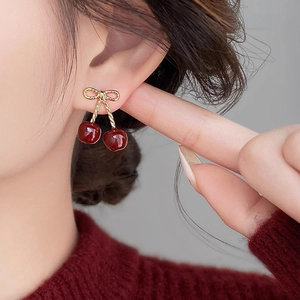 Sweet red resin cherry earrings with golden bow studs for a vintage look on model