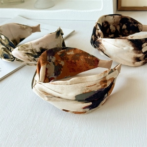 Three tie-dye marble print twisted wide headbands on a white wooden background