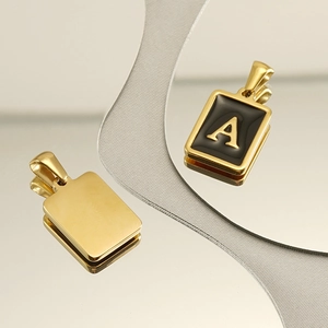 Close-up of 18K gold-plated rectangle pendant with letter A on mirrored surface