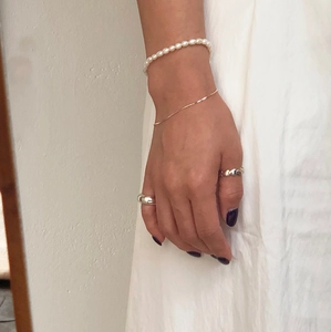 Detail of layered 925 sterling silver bracelets with freshwater pearls and heart rings