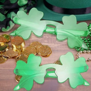 St. Patrick's Day party kit with shamrock glasses, green beads, and coins on wood background