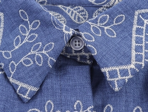 Détail du col d'une robe bleue de style français avec broderie et bouton à quatre trous