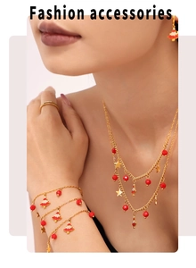 Detail of gold layered necklace and bracelet with red beads and Christmas tree charms