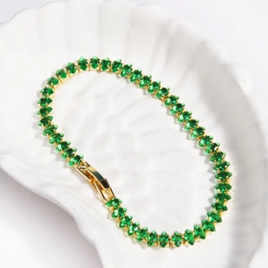 Close-up of emerald green marquise cut cubic zirconia tennis bracelet in gold setting