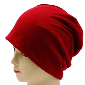 Detail view of a soft red knitted slouchy beanie hat shown on a display mannequin