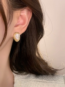 Close-up of French vintage irregular pearl ear clip on ear with golden frame detail