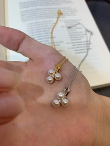Close-up of gold and silver pearl necklaces with three-petal zircon floral pendant design