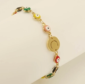 Detail of gold evil eye bracelet featuring multi-colored enamel beads and moon pendant