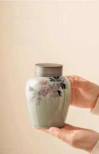Macro detail of hand-painted peach blossom tea caddy with crackle glaze and metal lid