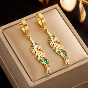 Macro detail of golden feather earrings with colorful enamel on a jewelry box