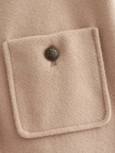 Close-up of wool fabric texture with embossed crest metal button on khaki jacket