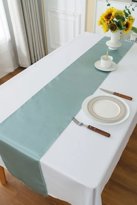 Close-up of a smooth light green satin table runner styled on a white tablecloth