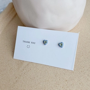 Macro detail of S925 sterling silver heart stud earring with blue enamel and crystal