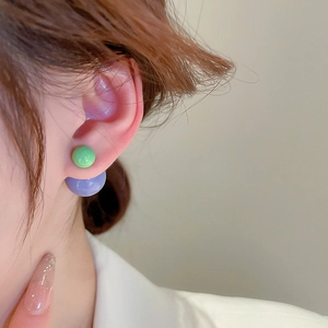 Detailed view of dual-bead green and purple acrylic earrings on ear showing fit