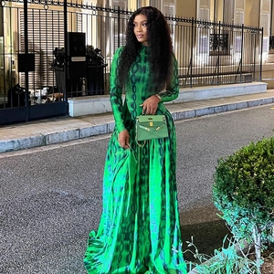 Detail of green printed maxi dress featuring a high neck and elegant long sleeves in a street setting