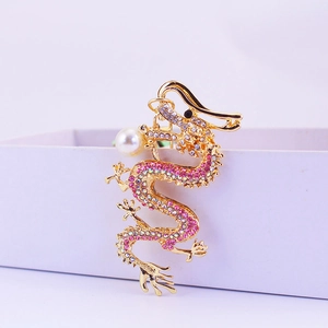 Golden dragon keychain with pink rhinestones and a white pearl accent on a gift box