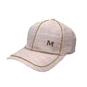 Elegant pink tweed baseball cap with pearl trim and golden letter M charm on white background