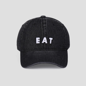 Detail of EAT letter embroidery on dark black washed denim baseball cap with texture