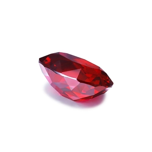 Oval cut synthetic pigeon blood ruby gemstone with faceted surface on white background