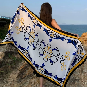 Detail of a rectangular polyester beach shawl with blue and yellow floral prints on the coast
