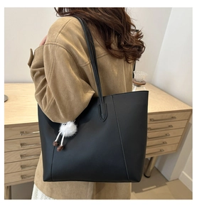 Détail d'un grand sac cabas noir en cuir synthétique mat avec charme en peluche