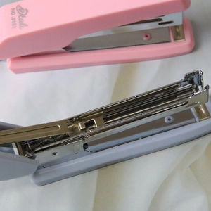 Deli NO.0151 Morandi stapler with metal slide mechanism shown in pink and gray
