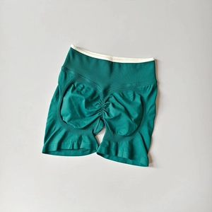 Close-up of seamless dark green yoga shorts featuring scrunch butt and white waistband