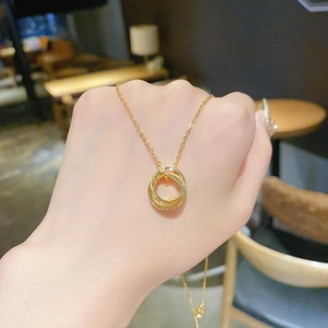 Close-up of interlocking triple ring pendant necklace on hand with gold metallic finish