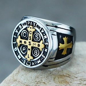 Macro shot of silver and gold Saint Benedict medal ring on natural stone background