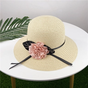 Top view of a woven straw sun hat with a delicate pink chiffon flower and black ribbon