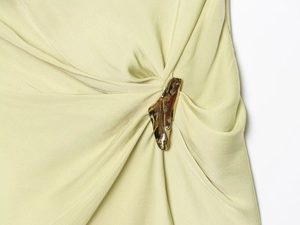 Detail of light green ruched fabric with a decorative gold metallic hardware accent