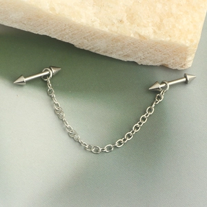 Detailed view of silver star ear chain featuring cone spikes and a metallic link chain