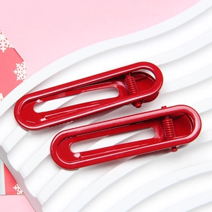 Close-up of vibrant red 6cm U-shaped metal hair clips on a decorative pink background