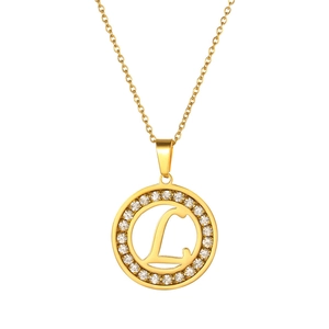 Detail shot of a golden circular pendant with sparkling diamonds and letter L engraved