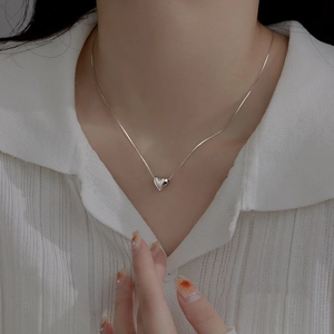 Close-up of minimalist S925 sterling silver heart pendant necklace on model neck
