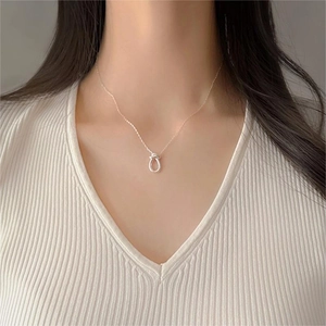 Close-up of minimalist S925 sterling silver knot pendant necklace worn by a model
