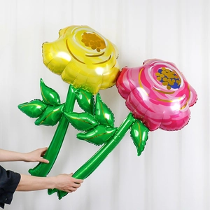 Close-up of pink and yellow daisy foil balloons with green stems for party decor