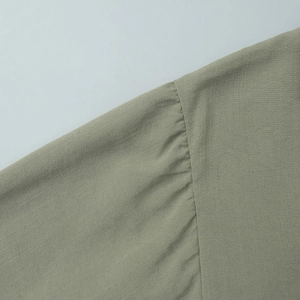 Close-up of knitted fabric texture and gathered seam detail in sage green color