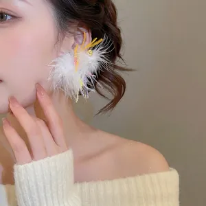 Elegant white feather drop earrings with colorful accents worn by a female model