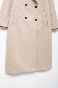 Détail de manteau en laine beige avec boutons contrastés et poches latérales chic