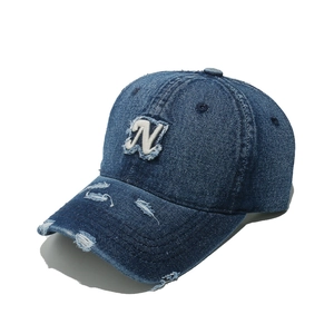 Detailed macro view of vintage distressed denim cap with N embroidery and torn brim