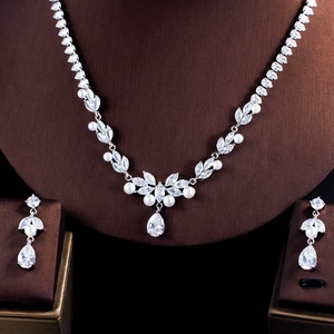 Detail of leaf-shaped jewelry set with pearls and zircons on a brown display stand