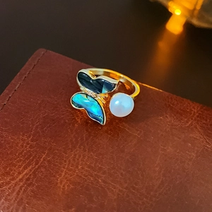 Macro detail of gold butterfly ring with iridescent abalone shell and white pearl inlay