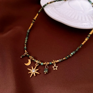 Detail of vintage beaded necklace with celestial gold pendants on brown silk